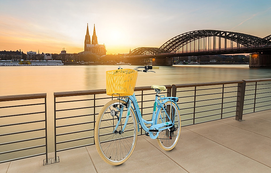 Fahrrad steht angelehnt am Flußufer vor einer City-Skyline
