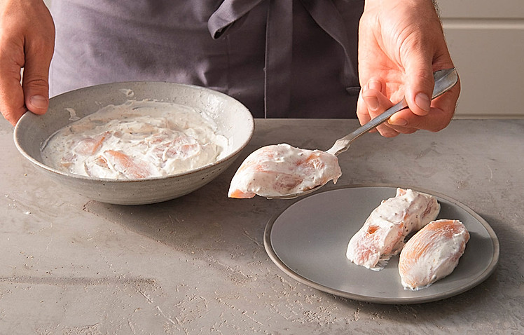 4. Die Hähnchenstücke aus der Marinade nehmen und den Gewürzjoghurt leicht von den Hähnchenbruststücken abstreifen. Das Fleisch mit Salz würzen.