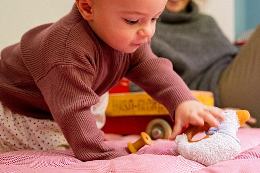 Baby spielt mit einem Greifspielzeug von Käthe Kruse
