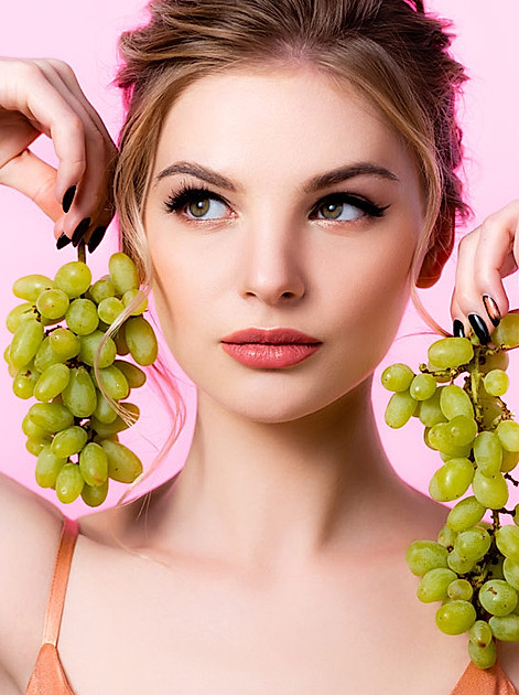 Junge Frau mit Weintrauben, deren Kerne wertvolle Nährstoffe bereithalten